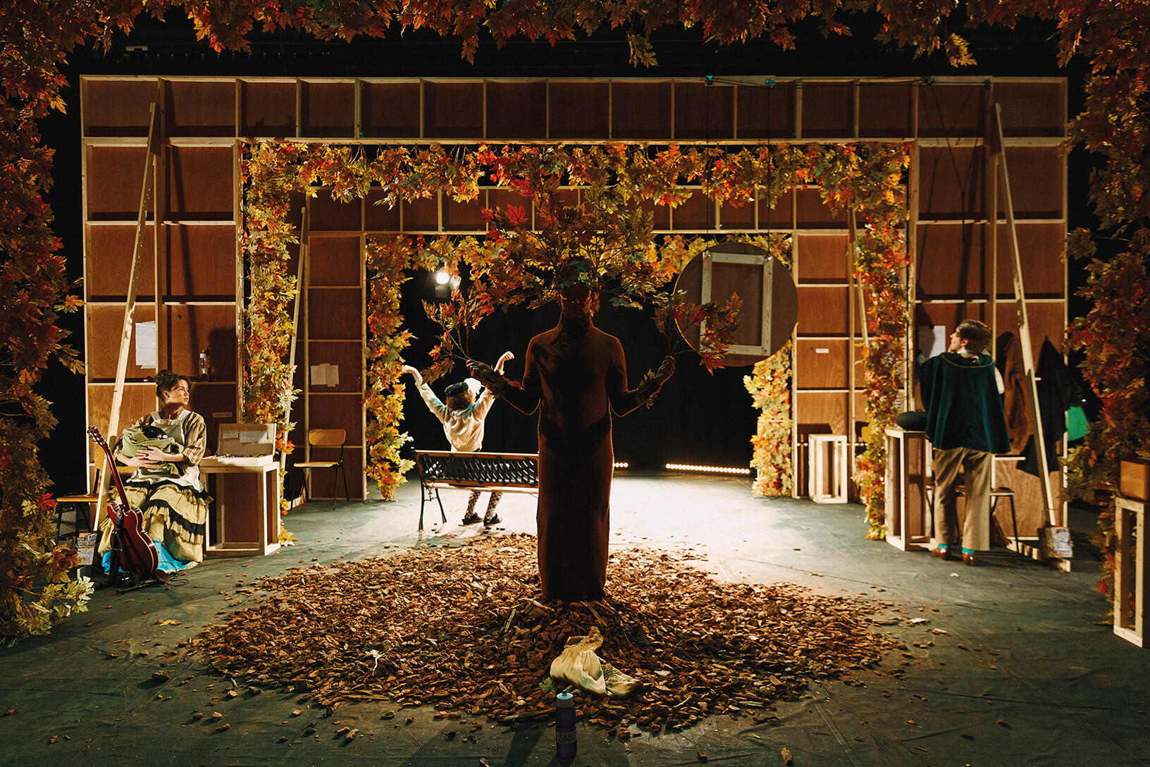 Persoon staand in hoop bladeren voor de achterkant van een decor in herfstsfeer
