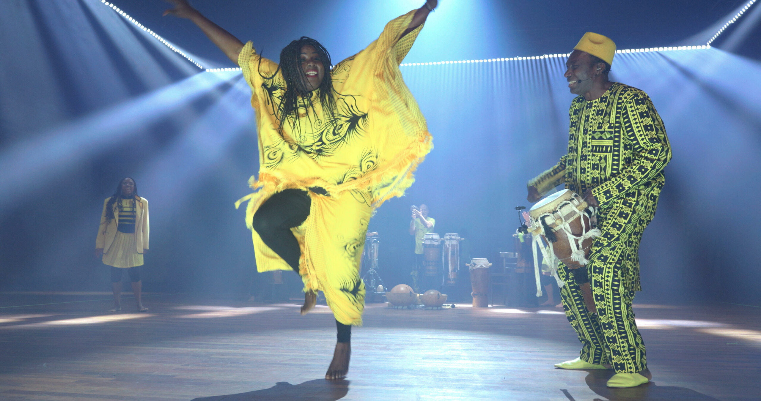 Een vrouw die in geel gekleed is, danst op het geluid van een drum